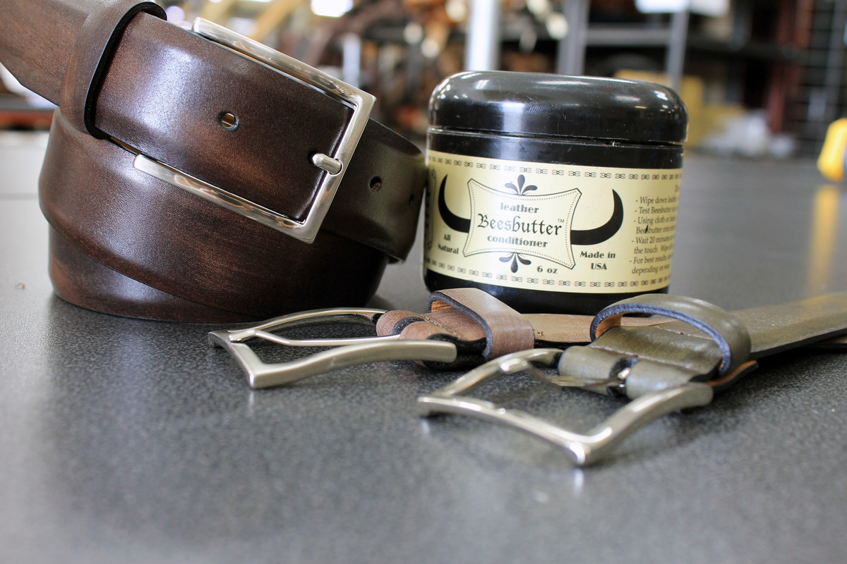brown remo tulliani jackson belt coiled next to leather butter container with two belts 